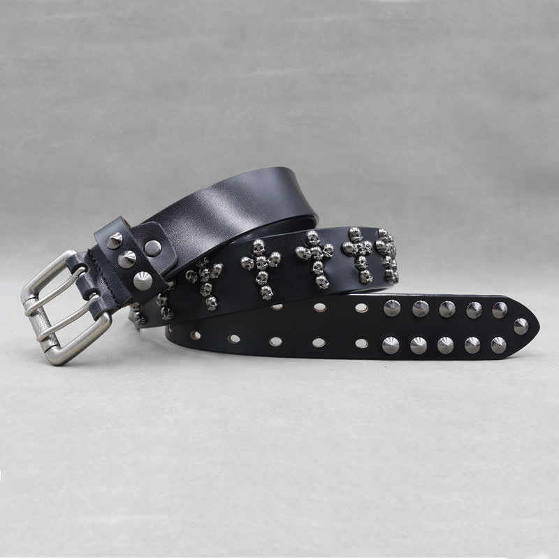Cinturón de cuero con remaches y doble pasador con forma de cruz y cabezas de calavera.