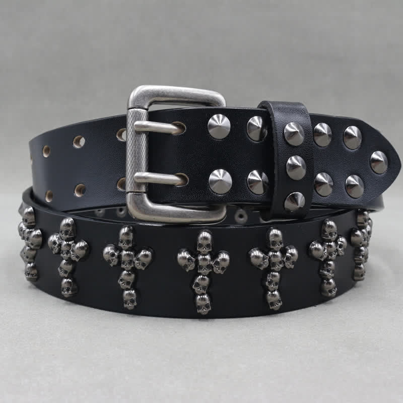 Cinturón de cuero con remaches y doble pasador con forma de cruz y cabezas de calavera.