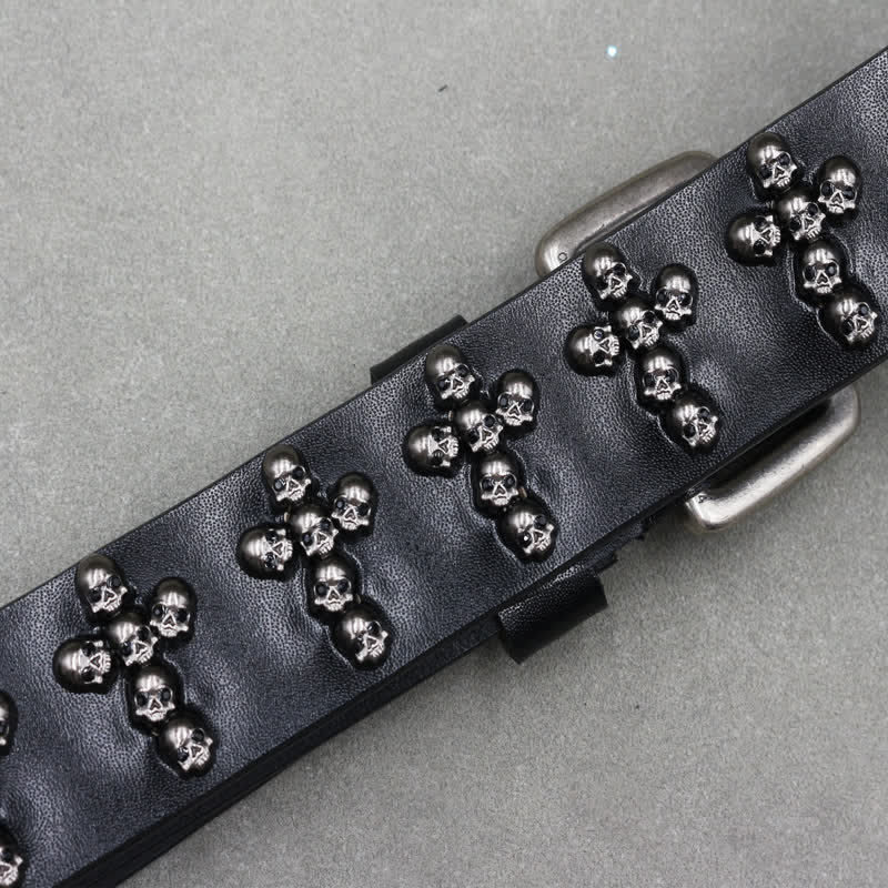Cinturón de cuero con remaches y doble pasador con forma de cruz y cabezas de calavera.