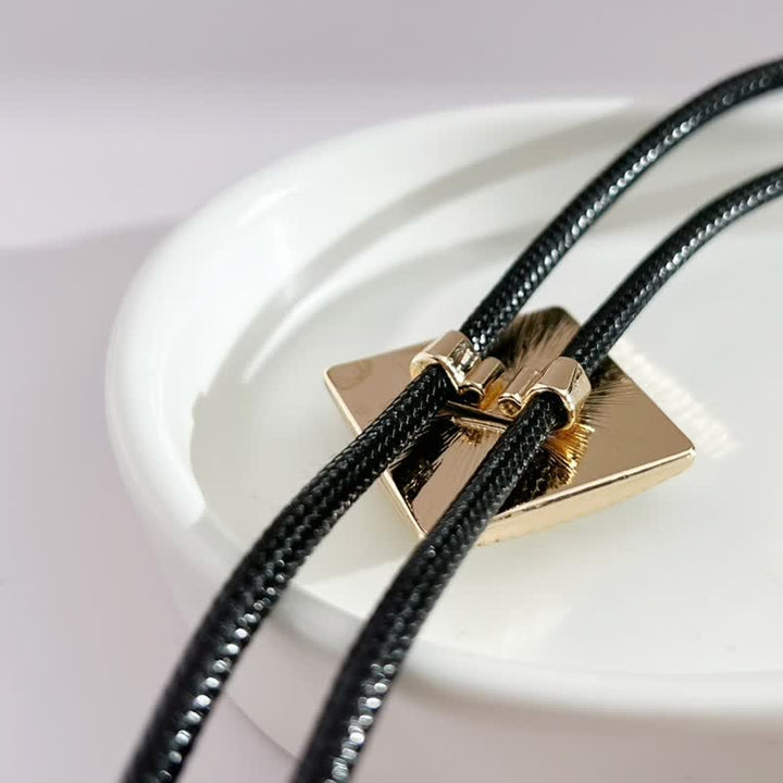 Corbata bolo con forma de diamante y estampado de flores doradas.