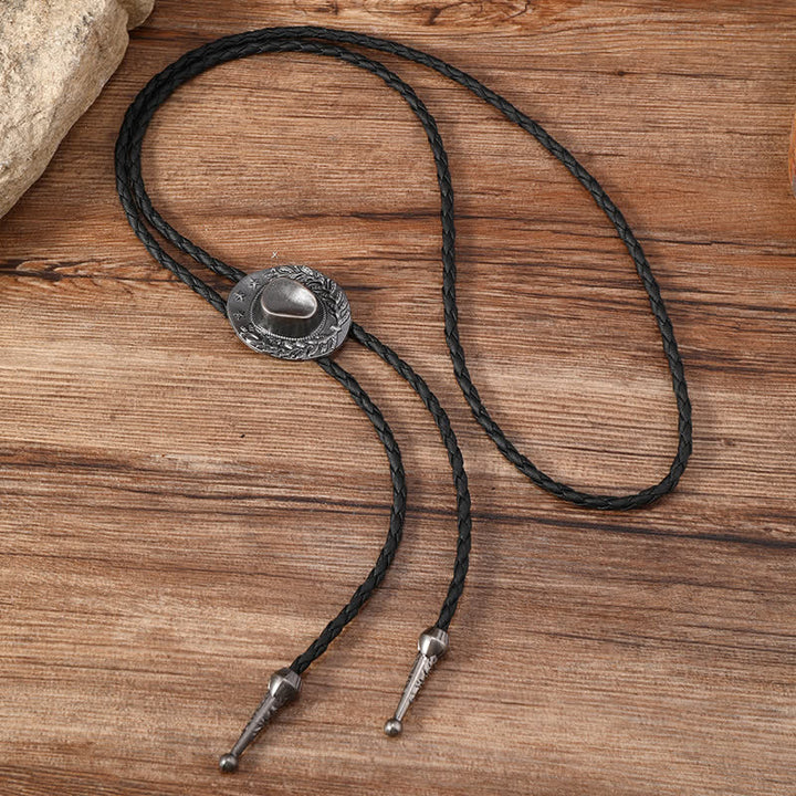 Dije de bronce con forma de sombrero de vaquero y corbata de bolo
