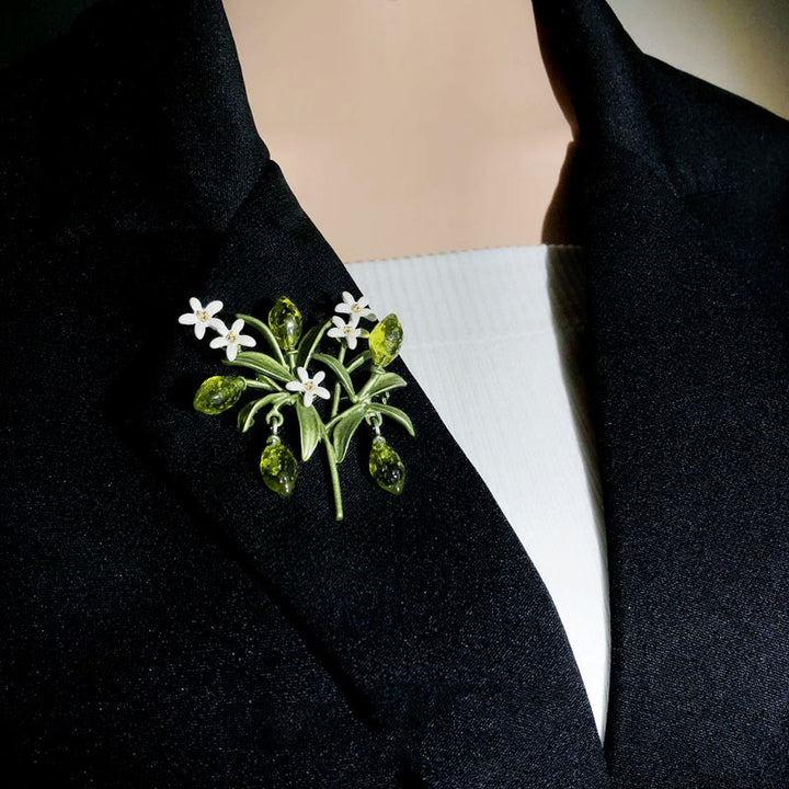 Broche de mujer con forma de gota de limón y planta verde.