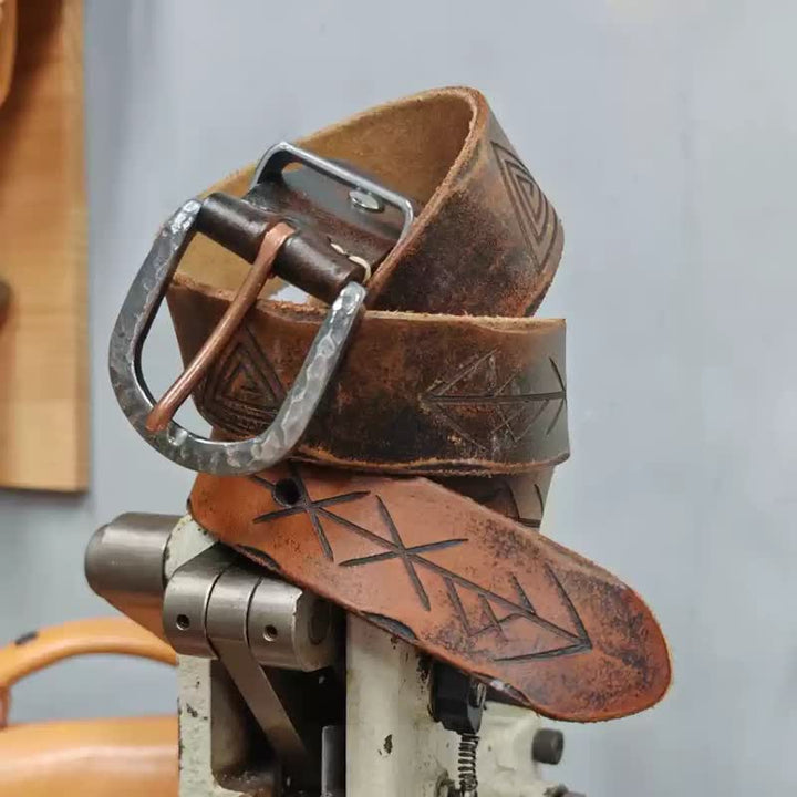 Cinturón de cuero con diseño de flecha tallada y hebilla de martillo de plata.