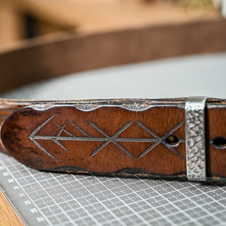 Cinturón de cuero con diseño de flecha tallada y hebilla de martillo de plata.