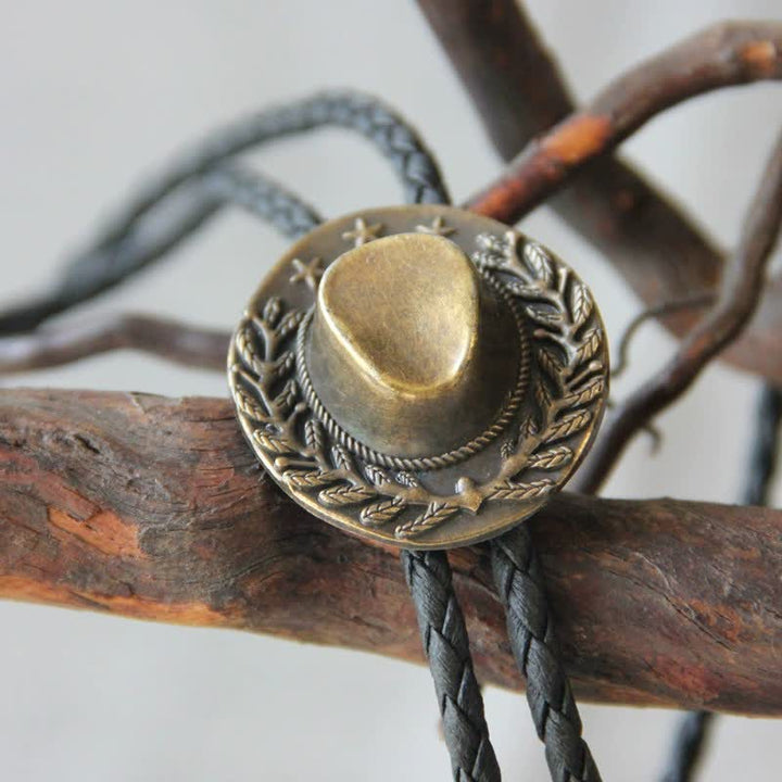 Dije de bronce con forma de sombrero de vaquero y corbata de bolo