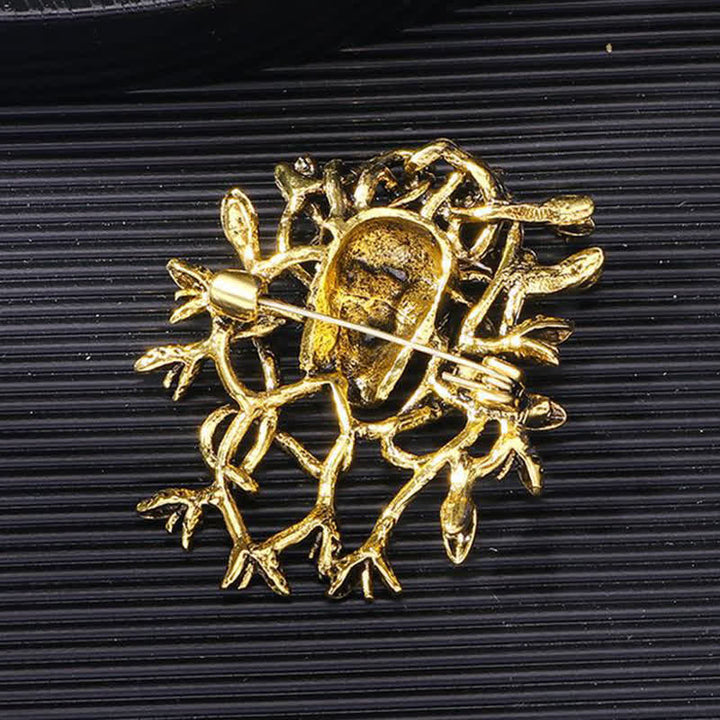 Broche exagerado de calavera con cabeza de serpiente envuelta