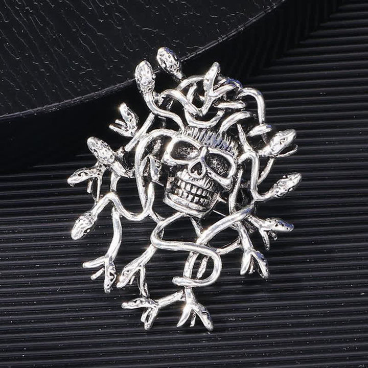 Broche exagerado de calavera con cabeza de serpiente envuelta