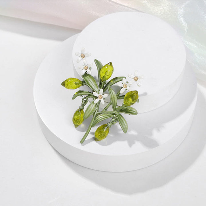 Broche de mujer con forma de gota de limón y planta verde.