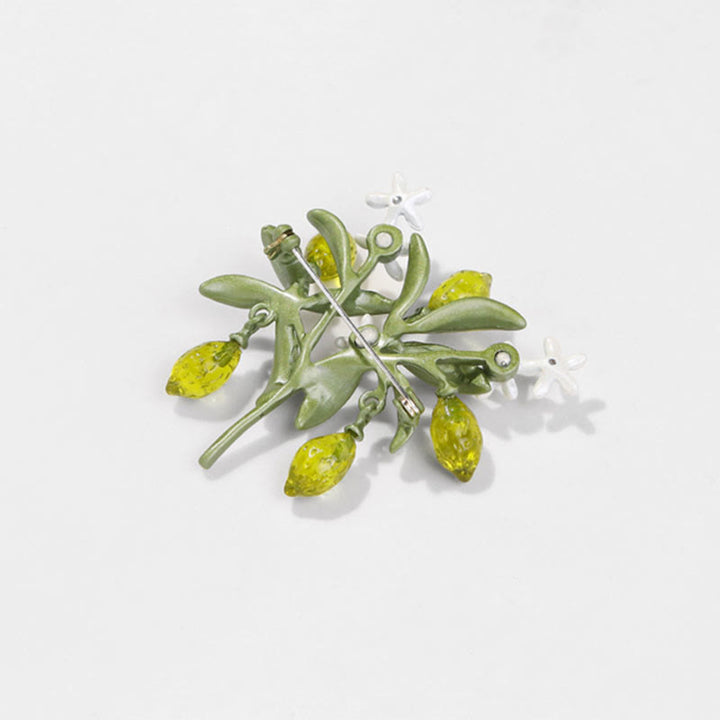 Broche de mujer con forma de gota de limón y planta verde.