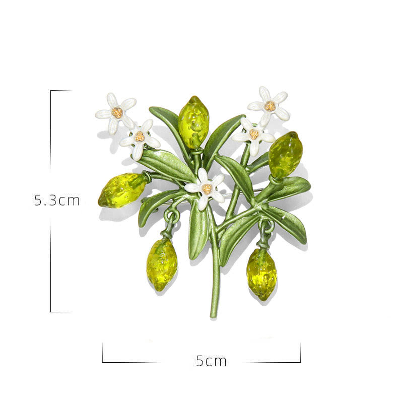 Broche de mujer con forma de gota de limón y planta verde.