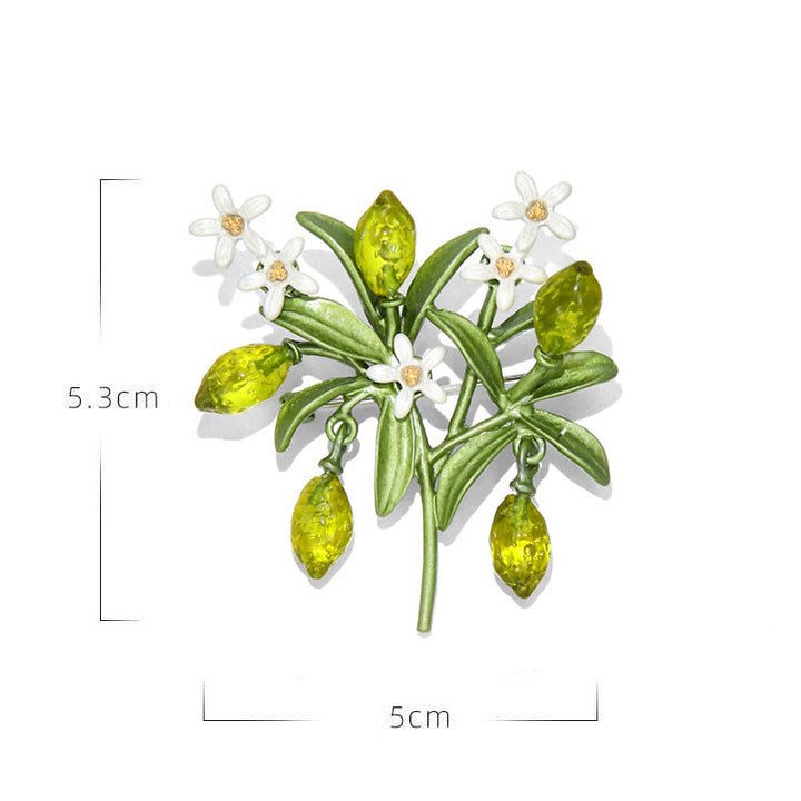 Broche de mujer con forma de gota de limón y planta verde.