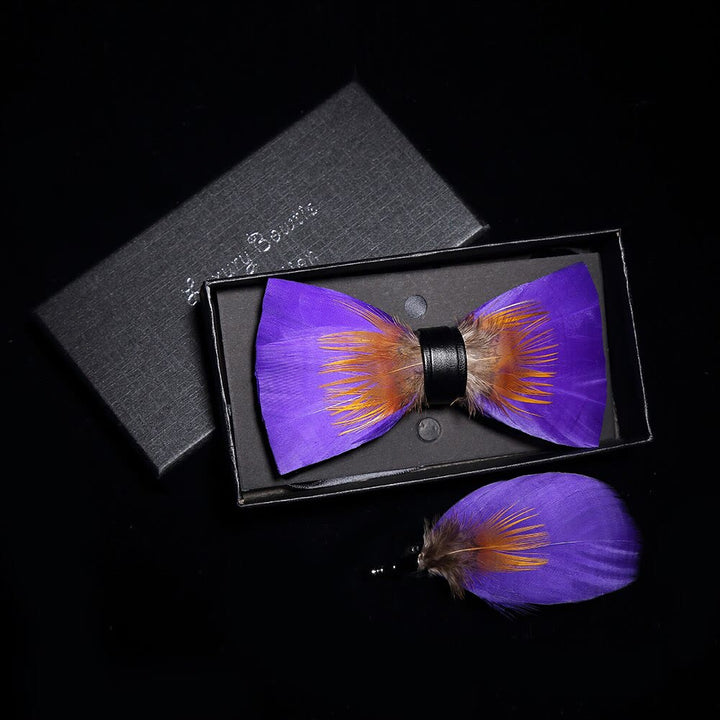 Pajarita con plumas y adornos morados y naranjas con broche de solapa