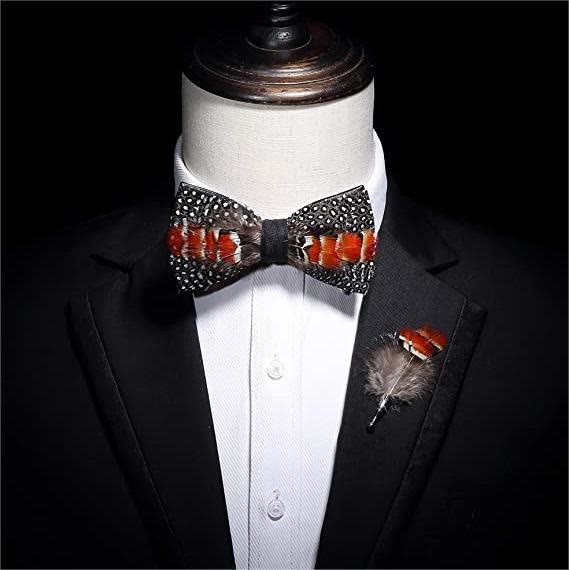 Pajarita con plumas de lunares en blanco, naranja y negro y broche de solapa