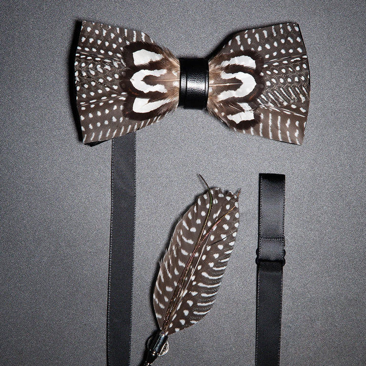 Pajarita de plumas con lunares marrones y blancos y broche de solapa